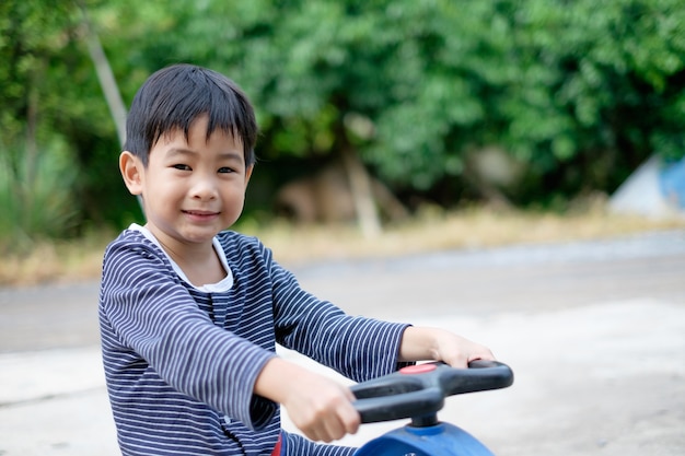 Rapaz asiático sorrir e andar de carro de brinquedo na estrada