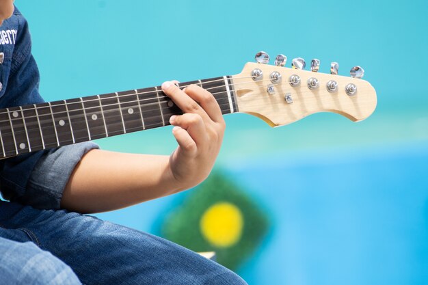 Rapaz asiático tocando guitarra