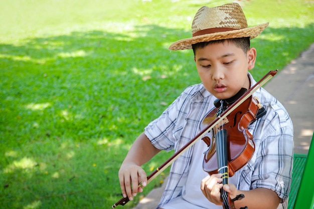 Rapaz asiático tocando música de violino no jardim