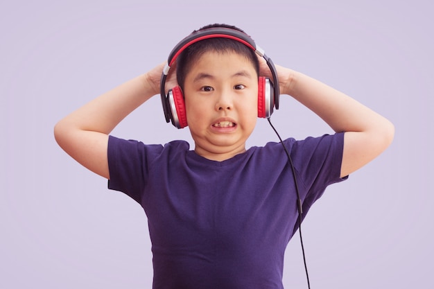 Rapaz asiático usando fones de ouvido, ouvindo música e louco e gritando animado, isolado no fundo cinza