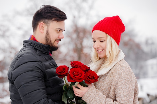 Rapaz bonito dando um buquê de rosas para uma garota no dia dos namorados