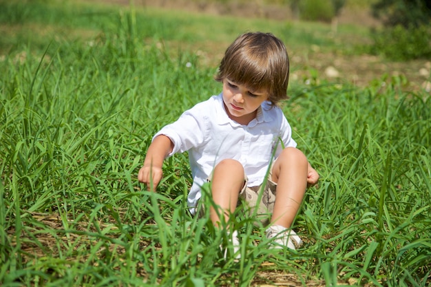 Rapaz bonito sentado na grama