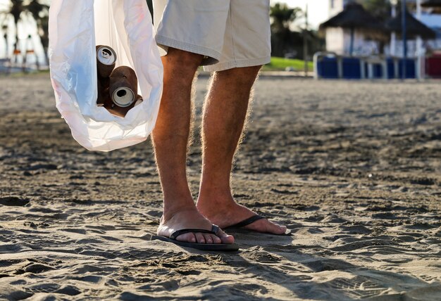 Rapaz com saco de lixo e latas enferrujadas dentro de casa na praia