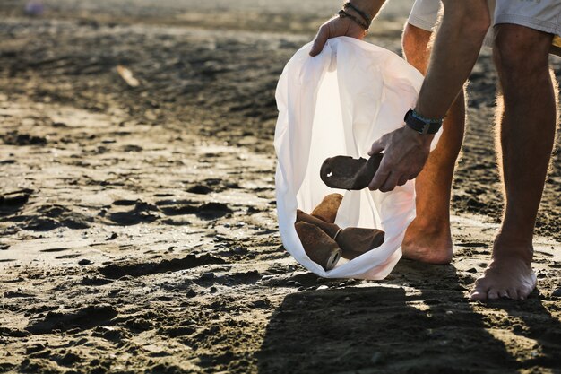 Rapaz com saco de lixo e latas enferrujadas dentro de casa na praia