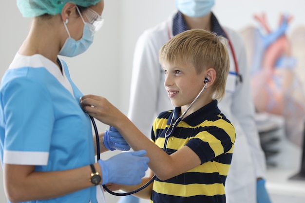 Rapaz com uma t-shirt às riscas ouve os batimentos cardíacos do médico com um estetoscópio preto