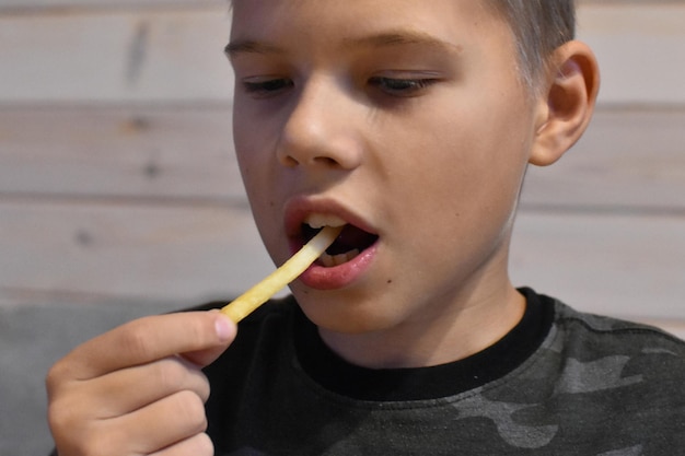 Foto rapaz comendo delicioso hambúrguer de fast food com batatas fritas.