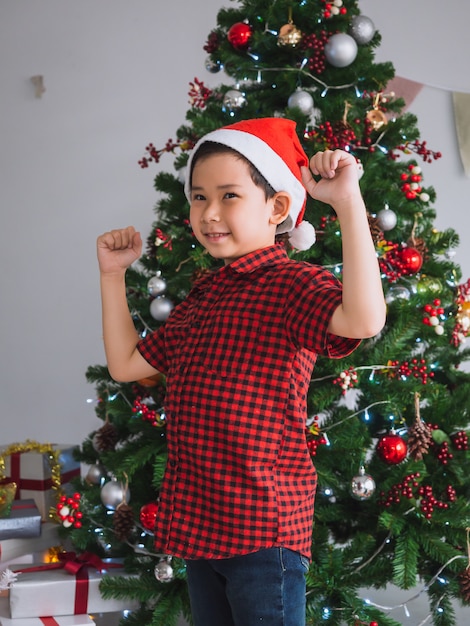 Foto rapaz de camisa vermelha é feliz e engraçado para celebrar o natal com árvore de natal