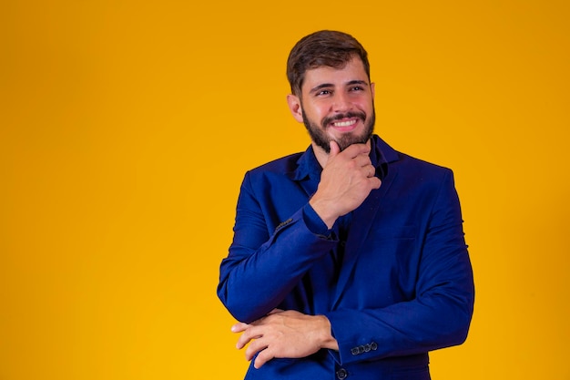 Rapaz de negócios jovem com terno azul royal em fundo amarelo