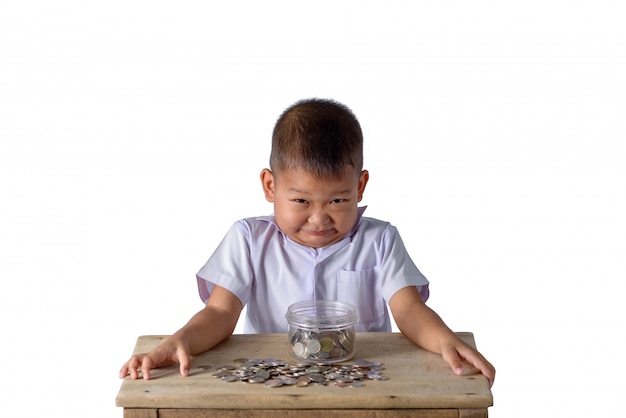 Rapaz do país asiático bonito divirta-se com moedas na tigela de vidro isolado no branco