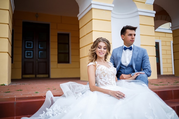 Rapaz elegante com a fantasia de noivo e noiva linda garota em um vestido branco com um passeio de trem no parque no dia do casamento