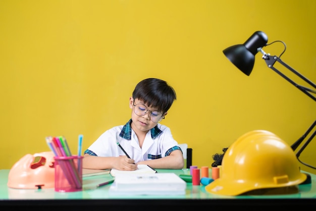 Rapaz fazendo lição de casa Na mesa há materiais de aprendizagem