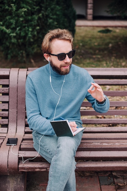 Rapaz jovem hipster gay percebe ideias em um parque