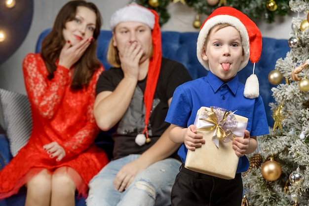 Rapaz mostra a língua com um presente de Natal