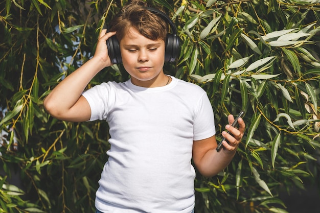 Rapaz na moda em fones de ouvido com smartphone ouvindo música no parque
