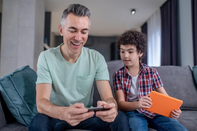 Rapaz olhando para smartphone de homem sentado perto