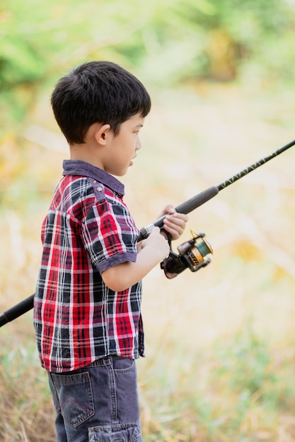 Rapaz pequeno bonito asiático que pesca em natural