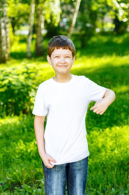 Foto rapaz pequeno feliz que aponta seus dedos em um t-shirt vazio.