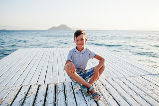 Rapaz sente-se no resort da Turquia no cais contra o mar Mediterrâneo