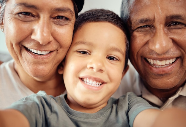 Rapaz tira selfie com avós felizes juntos em closeup ou retrato de zoom em casa, criança do sexo masculino latino sorri com vovó e vovô em macro com expressão de felicidade e amor na casa da família