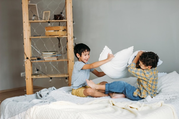 Rapazes a lutar com almofadas enquanto estão sentados na cama.