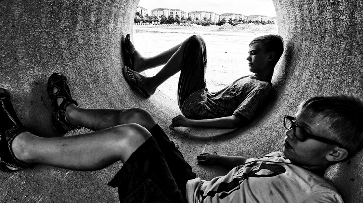 Foto rapazes deitados num cano de cimento
