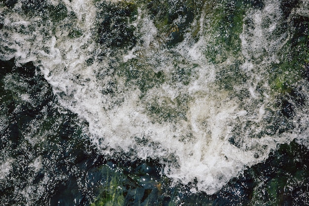 El rápido flujo de agua con olas blancas y burbujas de aire. Vista superior de una corriente de agua que fluye rápidamente.