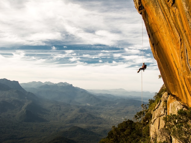 Rappel una pared de roca amarilla negativa con montañas