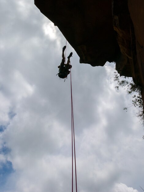 Rappel en una pared de roca sanstone negativa con cielo azul - vista desde abajo