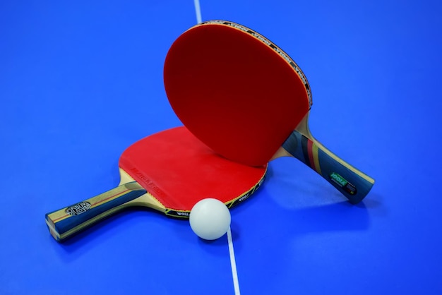 una raqueta roja y un ping pong en la mesa azul