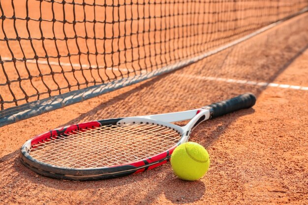 Raqueta de tenis y pelota cerca de la red en la cancha