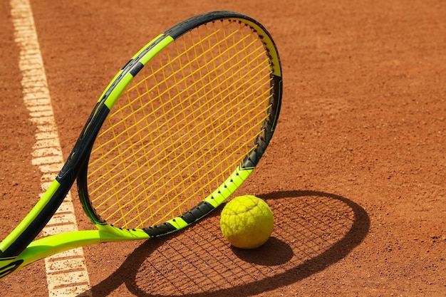 Raqueta de tenis y pelota de tenis en cancha de arcilla