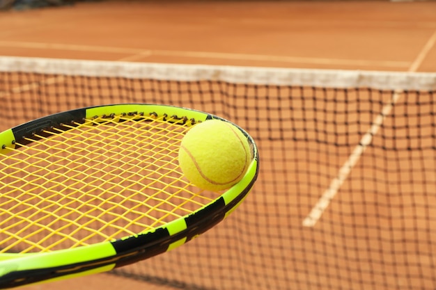 Raqueta de tenis con pelota de tenis contra tierra batida