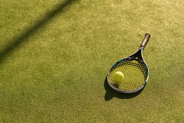 Una raqueta de tenis y una pelota de tenis nueva en una cancha de tenis recién pintada.