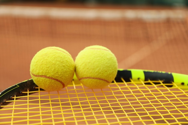 Raqueta de tenis con pelotas de tenis contra tierra batida