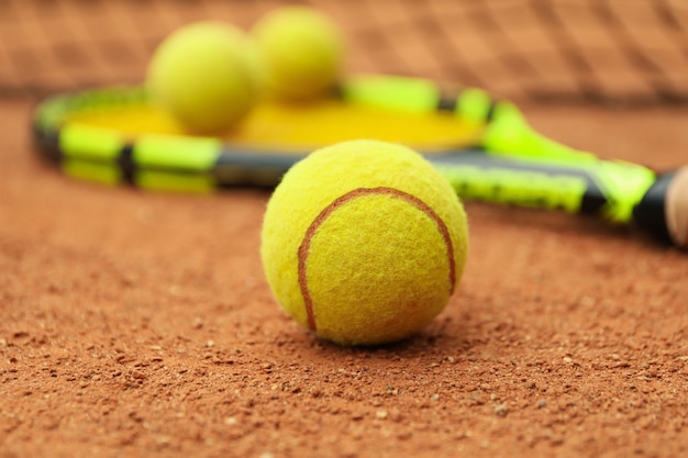 Raqueta de tenis con pelotas de tenis en tierra batida