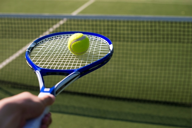 Raqueta de tenis de primer plano con la pelota