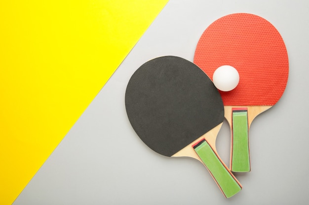 Raquetas y pelotas de ping pong en superficie gris y amarilla