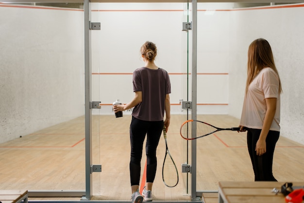 Raquetas de squash en la mesa, jugadores de fondo