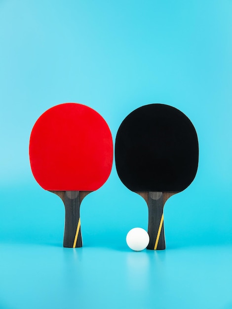 Foto raquetas de tenis y una pelota de ping-pong sobre un fondo azul