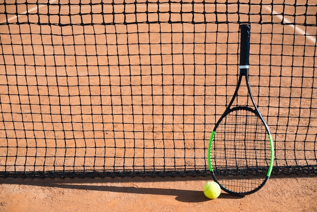 Foto raquete de tênis de ângulo alto restin na rede de tênis