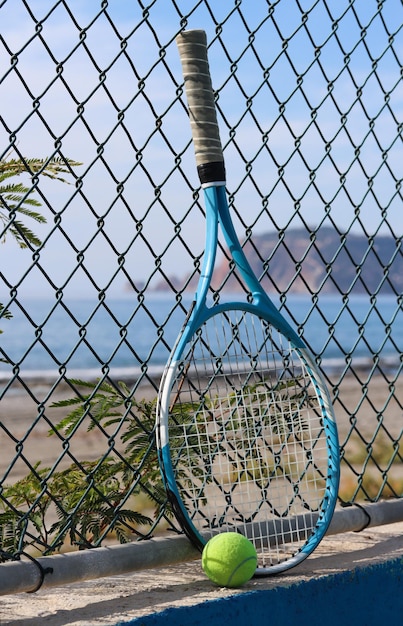 Raquete e bola na praia em frente ao mar e montanha em um dia ensolarado. Conceito de esporte de verão