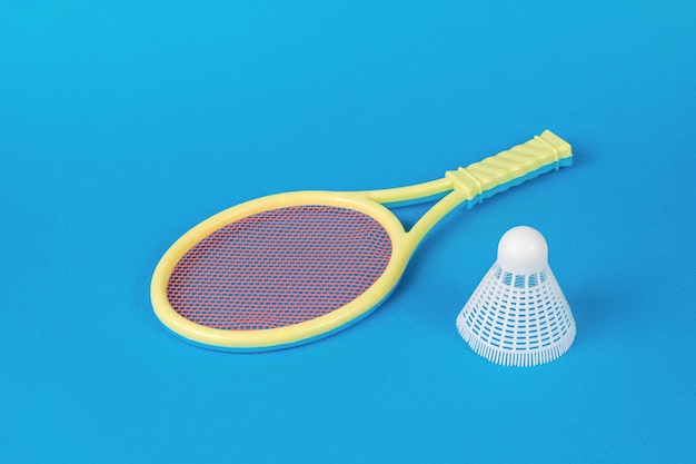 Raquetes amarelas e uma peteca de badminton branca sobre fundo azul