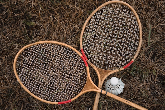 Raquetes de badminton de madeira e uma peteca de penas brancas O jogo de badminton