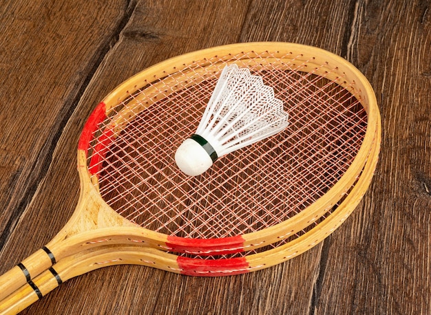 Foto raquetes de madeira e um taco de plástico para jogar badminton em um fundo de madeira