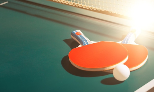 Raquetes de tênis de mesa e bola na mesa com rede