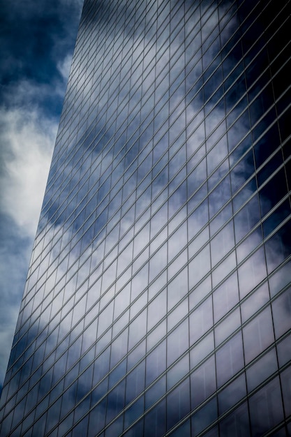 rascacielos con fachada de cristal y nubes reflejadas en las ventanas