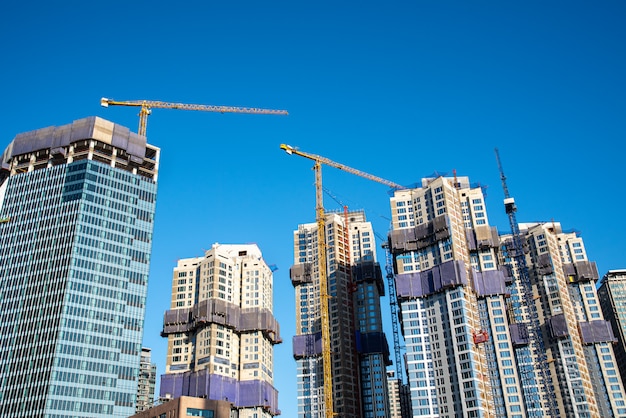 Rascacielos modernos en construcción con grúas torre. Concepto de industria.