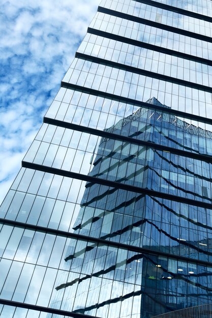 Foto rascacielos de oficinas de cristal, en cuyas ventanas se refleja el rascacielos vecino.