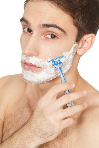 Rasierroutine. Kopf und Schultern Studioaufnahme eines jungen gutaussehenden Mannes, der sein Gesicht isoliert auf Weiß rasiert