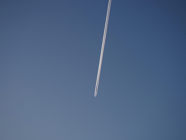 El rastro de un avión que vuela en el cielo Cielo azul de la tarde Emisiones de queroseno o combustible para cohetes de heptilo Concepto ambiental Negocios de aviación y transporte de pasajeros